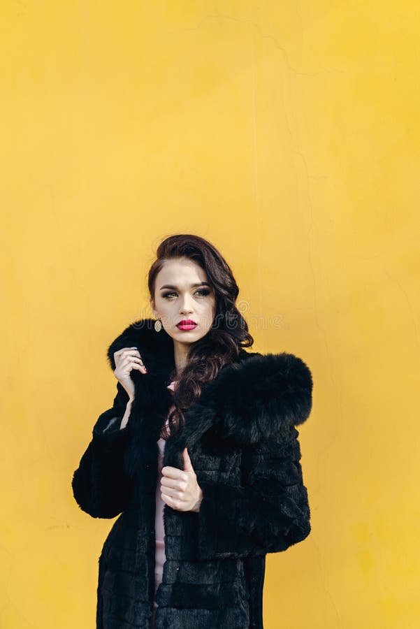 Mooi meisje in een zwarte bontjas Gele achtergrond stock foto's Mooi meisje in een zwarte bontjas Gele achtergrond stock foto's