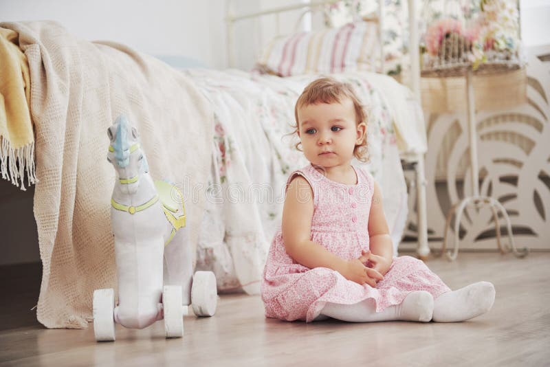 Mooi meisje het spelen speelgoed Blauw-eyed blonde Witte stoel Kinderen` s ruimte Gelukkig klein meisjesportret Kinderjaren royalty-vrije stock foto Mooi meisje het spelen speelgoed Blauw-eyed blonde Witte stoel Kinderen` s ruimte Gelukkig klein meisjesportret Kinderjaren royalty-vrije stock foto