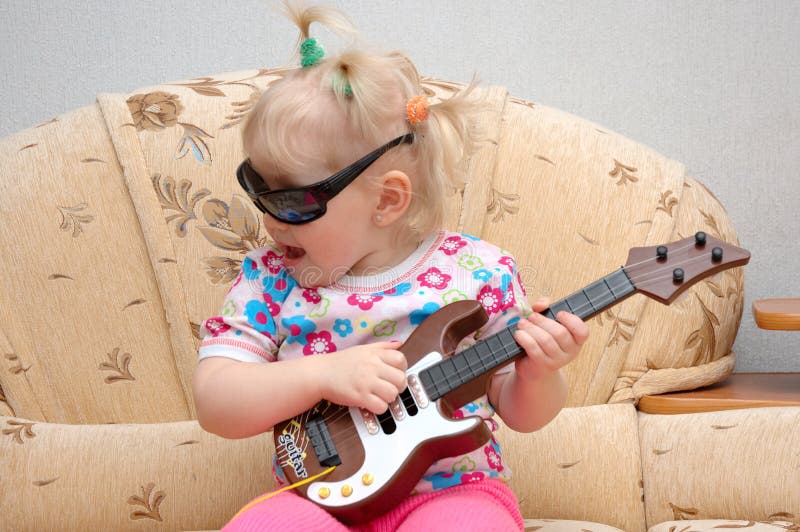 Mooi meisjespel op stuk speelgoed gitaar. stock afbeeldingen Mooi meisjespel op stuk speelgoed gitaar. stock afbeeldingen