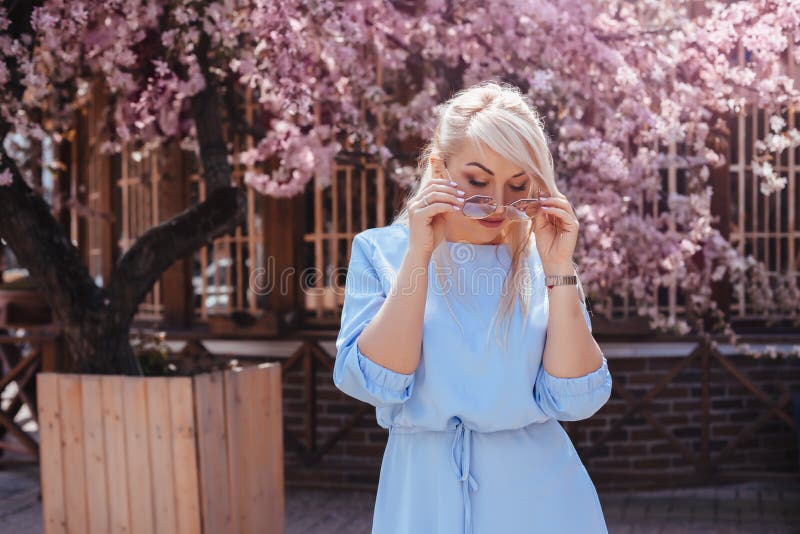 Mooi model in blauwe kleding door de lente bloeiende boom stock foto Mooi model in blauwe kleding door de lente bloeiende boom stock foto