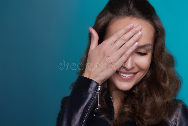 Mooi schuw meisje met het glanzen glimlach op een blauwe achtergrond stock fotografie Mooi schuw meisje met het glanzen glimlach op een blauwe achtergrond stock fotografie