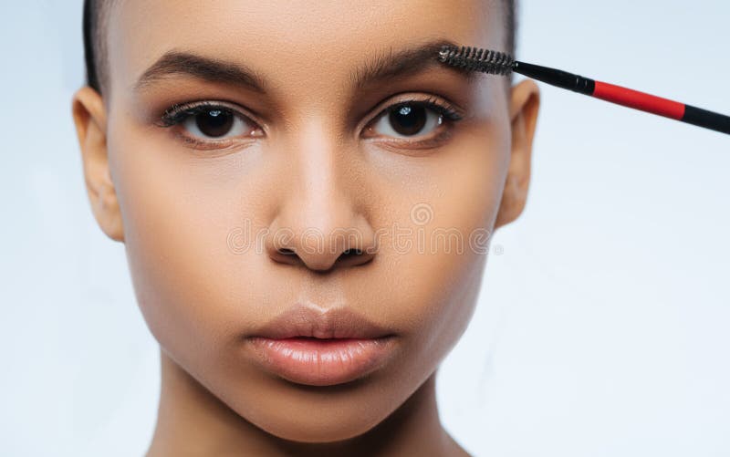 Perfect shape. Beautiful nice brunette woman looking at you and using special brush while making the shape of her eyebrows perfect. Perfect shape. Beautiful nice brunette woman looking at you and using special brush while making the shape of her eyebrows perfect