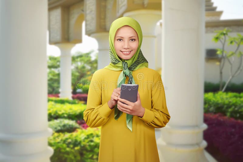Mooie Aziatische moslimvrouw die mobiele telefoon met behulp van stock fotografie Mooie Aziatische moslimvrouw die mobiele telefoon met behulp van stock fotografie