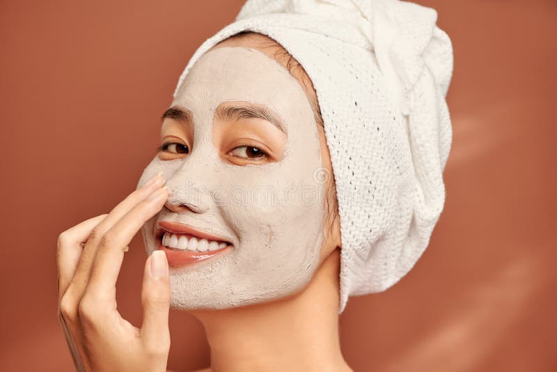 Beautiful Asian woman applying facial mask on her face. Skin care and treatment, spa, natural beauty and cosmetology concept. Beautiful Asian woman applying facial mask on her face. Skin care and treatment, spa, natural beauty and cosmetology concept.