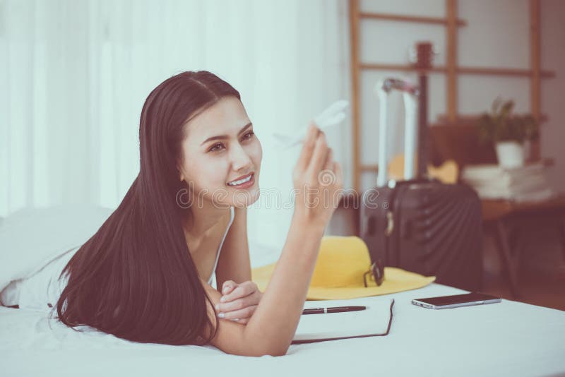 Mooie Aziatische vrouwenhanden die vliegtuigmodel houden en vakantie met reistoebehoren plannen op bed royalty-vrije stock foto's Mooie Aziatische vrouwenhanden die vliegtuigmodel houden en vakantie met reistoebehoren plannen op bed royalty-vrije stock foto's