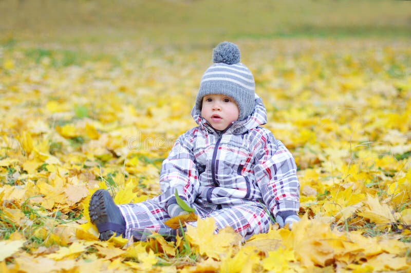Mooie babyleeftijd van 1 jaar in openlucht in de herfst tegen bladeren royalty-vrije stock fotografie