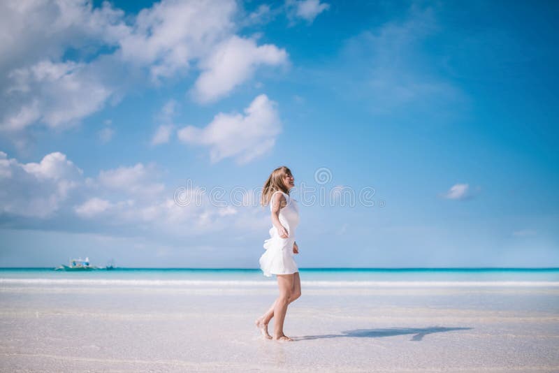 Beautiful blond long hair woman dancing on the beach. Happy island lifestyle. White sand, blue cloudy sky and crystal sea of tropical beach. Vacation on the paradise island. Beautiful blond long hair woman dancing on the beach. Happy island lifestyle. White sand, blue cloudy sky and crystal sea of tropical beach. Vacation on the paradise island.