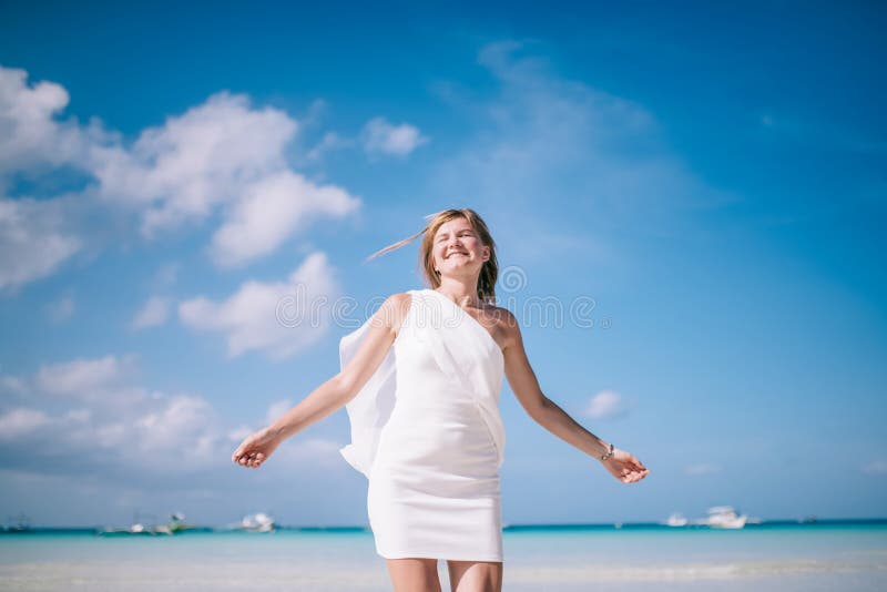 Beautiful blond long hair woman dancing on the beach. Happy island lifestyle. White sand, blue cloudy sky and crystal sea of tropical beach. Vacation on the paradise island. Beautiful blond long hair woman dancing on the beach. Happy island lifestyle. White sand, blue cloudy sky and crystal sea of tropical beach. Vacation on the paradise island.