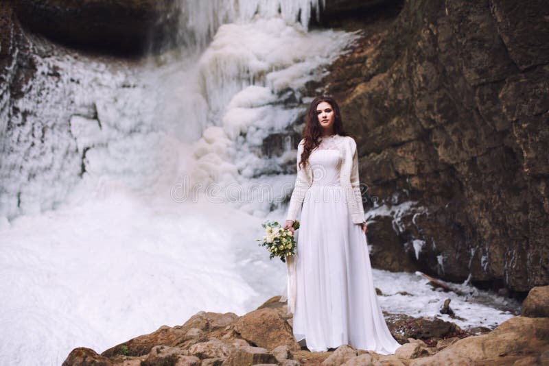Mooie bruid met een huwelijksboeket van bloemen op een achtergrond met een gletsjer en bergen royalty-vrije stock fotografie Mooie bruid met een huwelijksboeket van bloemen op een achtergrond met een gletsjer en bergen royalty-vrije stock fotografie