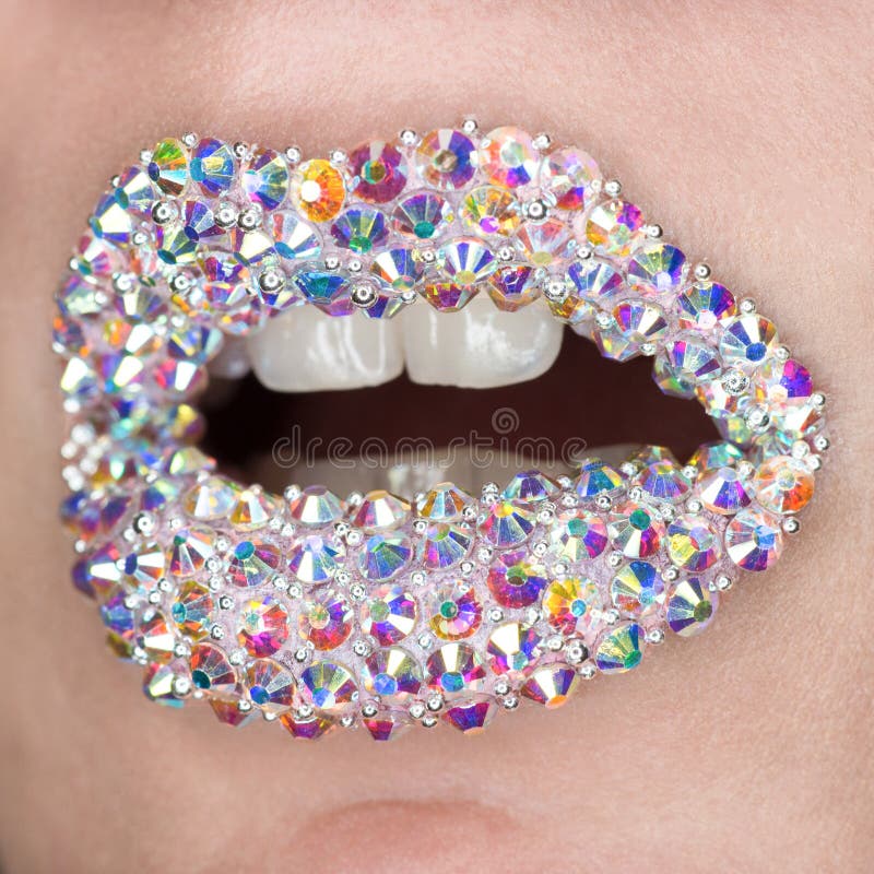 Mooie close-up met vrouwelijke lippen met witte colorfullhalfedelstenen Open mond met witte tanden Samenstelling, lippenart. royalty-vrije stock afbeelding Mooie close-up met vrouwelijke lippen met witte colorfullhalfedelstenen Open mond met witte tanden Samenstelling, lippenart. royalty-vrije stock afbeelding