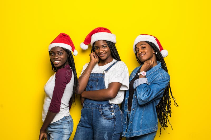 Mooie drie afrikaanse vrouwen in santa hat met kerststemming geïsoleerd op gele achtergrond stock foto Mooie drie afrikaanse vrouwen in santa hat met kerststemming geïsoleerd op gele achtergrond stock foto