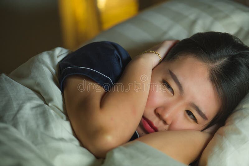 Mooie droevige en gedeprimeerde Aziatische Chinese vrouw wakker in bed laat - nacht die bezorgdheids aan crisis en het gevoel van royalty-vrije stock afbeelding Mooie droevige en gedeprimeerde Aziatische Chinese vrouw wakker in bed laat - nacht die bezorgdheids aan crisis en het gevoel van royalty-vrije stock afbeelding