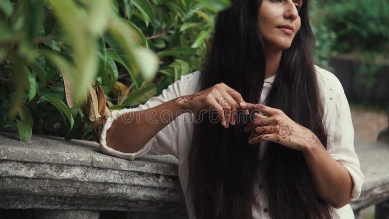 Mooie gelooide vrouw die op iemand in park met hennatatoegeringen wachten op haar handen