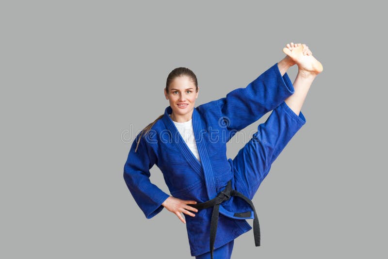 Mooie gelukkige atletische karatevrouw in blauwe kimono met zwarte stock afbeeldingen Mooie gelukkige atletische karatevrouw in blauwe kimono met zwarte stock afbeeldingen