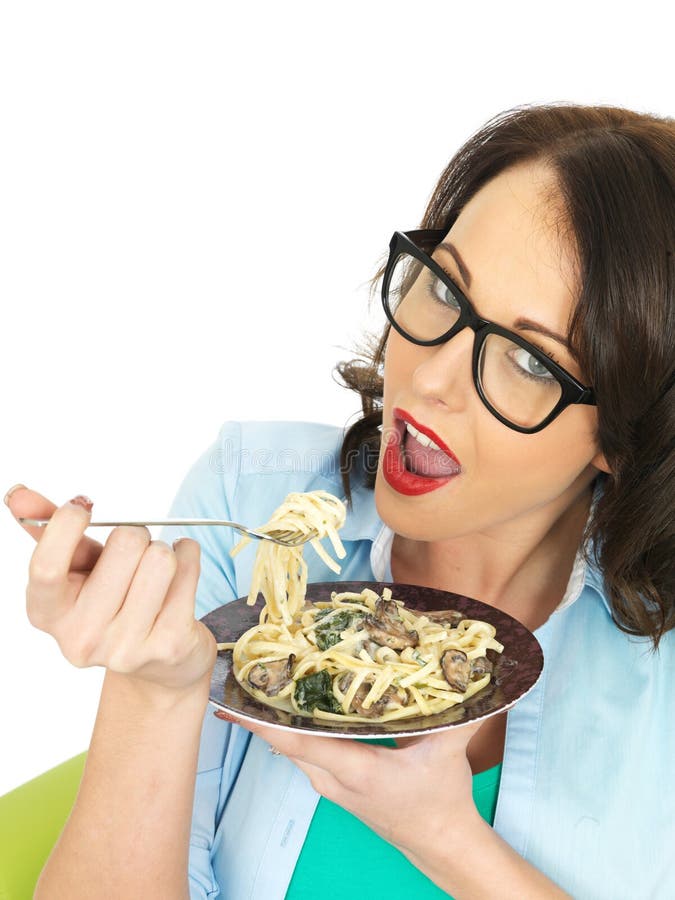 Mooie Gelukkige Jonge Spaanse Vrouw die een Plaat van Vegetarische Linguine met Spinazie en Paddestoelen eten royalty-vrije stock afbeelding Mooie Gelukkige Jonge Spaanse Vrouw die een Plaat van Vegetarische Linguine met Spinazie en Paddestoelen eten royalty-vrije stock afbeelding