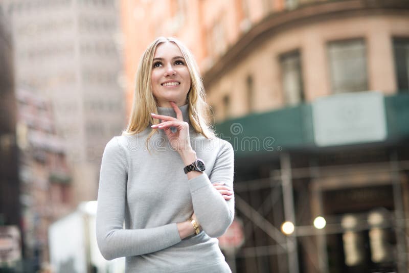 Mooie glimlachende blondevrouw die en op stadsstraat denken lopen stock afbeeldingen Mooie glimlachende blondevrouw die en op stadsstraat denken lopen stock afbeeldingen