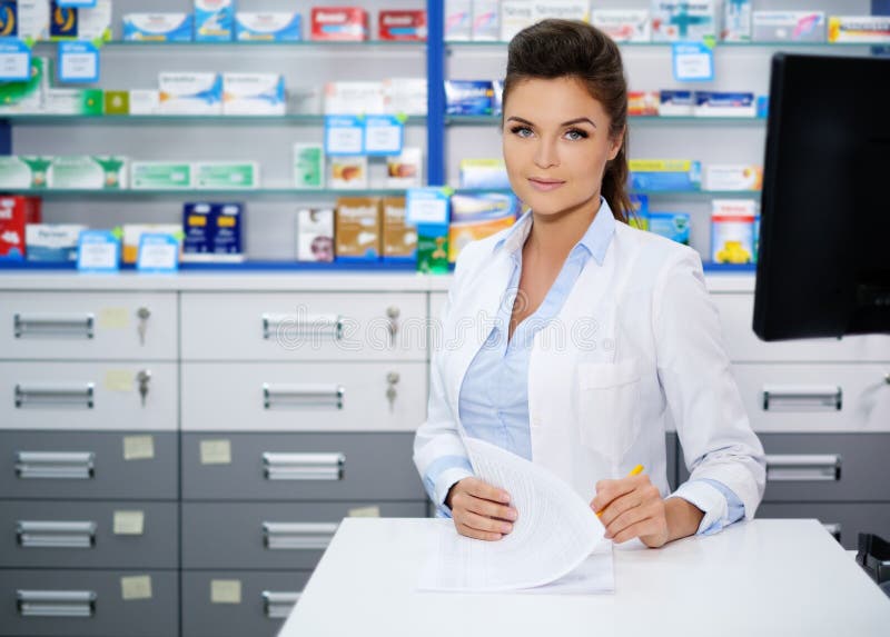 Mooie glimlachende jonge vrouwenapotheker die zijn werk in apotheek doen royalty-vrije stock fotografie Mooie glimlachende jonge vrouwenapotheker die zijn werk in apotheek doen royalty-vrije stock fotografie