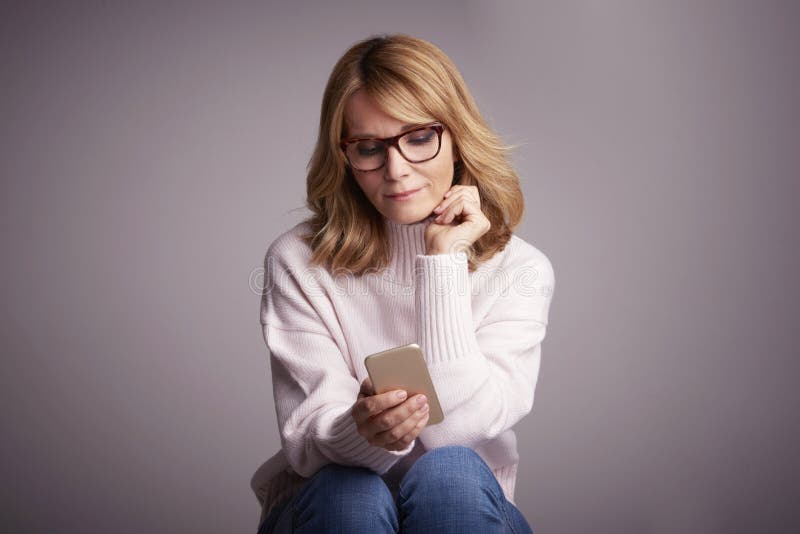 Mooie glimlachende vrouw die haar mobiele telefoon en tekstberichten gebruiken stock foto Mooie glimlachende vrouw die haar mobiele telefoon en tekstberichten gebruiken stock foto