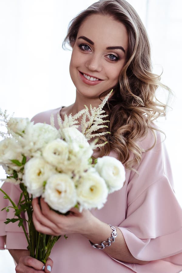 Mooie jonge blondevrouw met boeket van witte bloemen Portret van mooi blondemeisje in roze kleren stock fotografie Mooie jonge blondevrouw met boeket van witte bloemen Portret van mooi blondemeisje in roze kleren stock fotografie