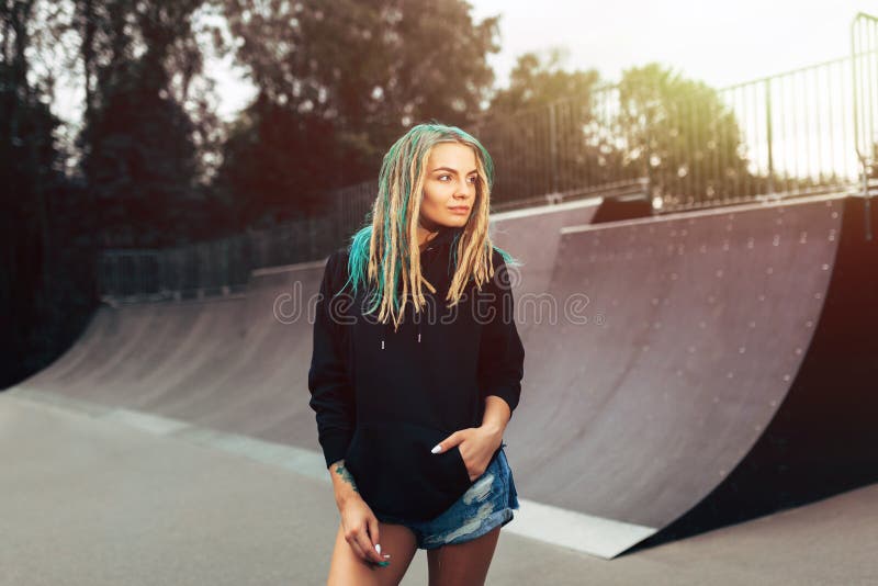 Mooie jonge geschiktheidsvrouw in het zwarte park van de hoodie bevindende vleet royalty-vrije stock foto Mooie jonge geschiktheidsvrouw in het zwarte park van de hoodie bevindende vleet royalty-vrije stock foto
