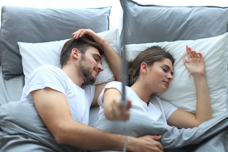 Mooie jonge het houden van paarslaap en het maken selfie met stok in het bed stock afbeeldingen Mooie jonge het houden van paarslaap en het maken selfie met stok in het bed stock afbeeldingen