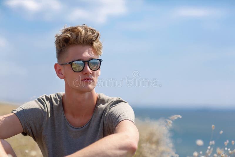 Mooie jonge mens op het gebied Modieuze, gezonde jongen op een natuurlijke achtergrond Uitgaand levensstijlconcept De ruimte van royalty-vrije stock foto Mooie jonge mens op het gebied Modieuze, gezonde jongen op een natuurlijke achtergrond Uitgaand levensstijlconcept De ruimte van royalty-vrije stock foto