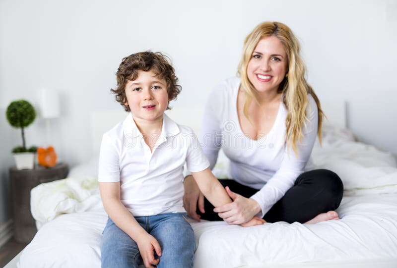 Mooie jonge moeder en zoon die samen op een bed liggen royalty-vrije stock afbeelding Mooie jonge moeder en zoon die samen op een bed liggen royalty-vrije stock afbeelding
