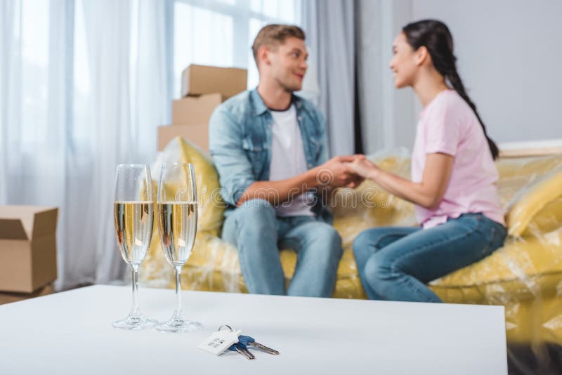 mooie jonge paarzitting op laag terwijl zich het bewegen in nieuw huis met champagneglazen en sleutels royalty-vrije stock afbeeldingen mooie jonge paarzitting op laag terwijl zich het bewegen in nieuw huis met champagneglazen en sleutels royalty-vrije stock afbeeldingen