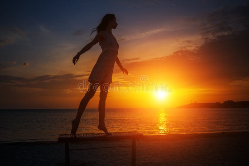 Mooie jonge slanke vrouw die zich op het strand bij zonsondergang bevinden, mooi silhouet tegen de hemel stock afbeeldingen Mooie jonge slanke vrouw die zich op het strand bij zonsondergang bevinden, mooi silhouet tegen de hemel stock afbeeldingen