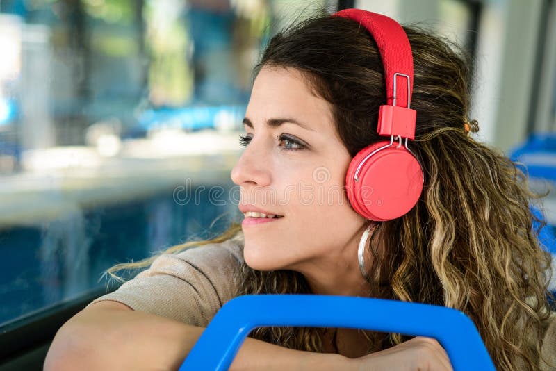 Mooie jonge vrouw die aan muziek in een trein luisteren stock foto Mooie jonge vrouw die aan muziek in een trein luisteren stock foto