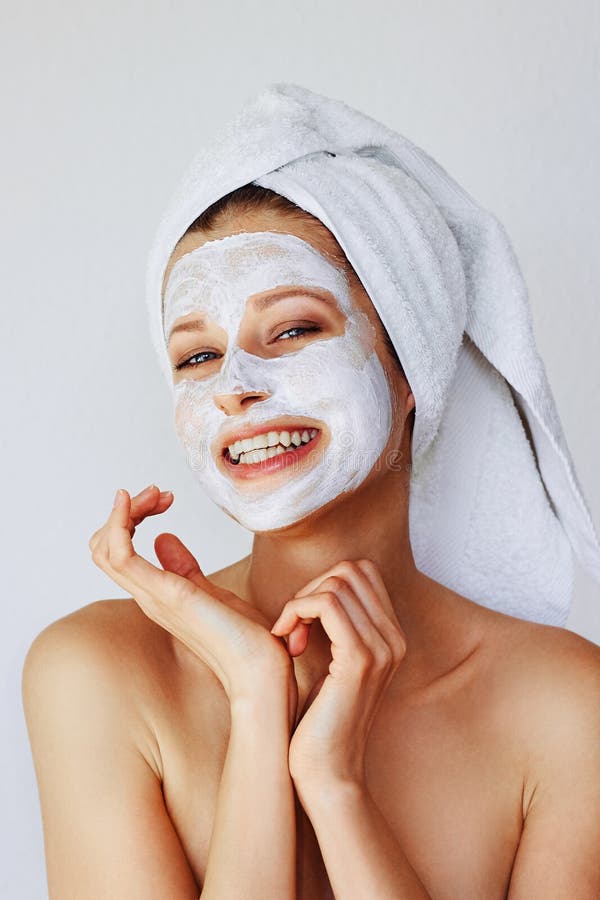 Beautiful young woman applying facial mask on her face. Skin care and treatment, spa, natural beauty and cosmetology concept, over white background. Beautiful young woman applying facial mask on her face. Skin care and treatment, spa, natural beauty and cosmetology concept, over white background