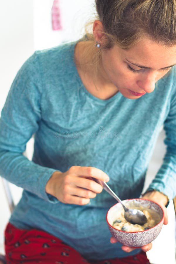 mooie jonge vrouw die graangewassen voor ontbijt in haar Pyjama eten stock fotografie mooie jonge vrouw die graangewassen voor ontbijt in haar Pyjama eten stock fotografie