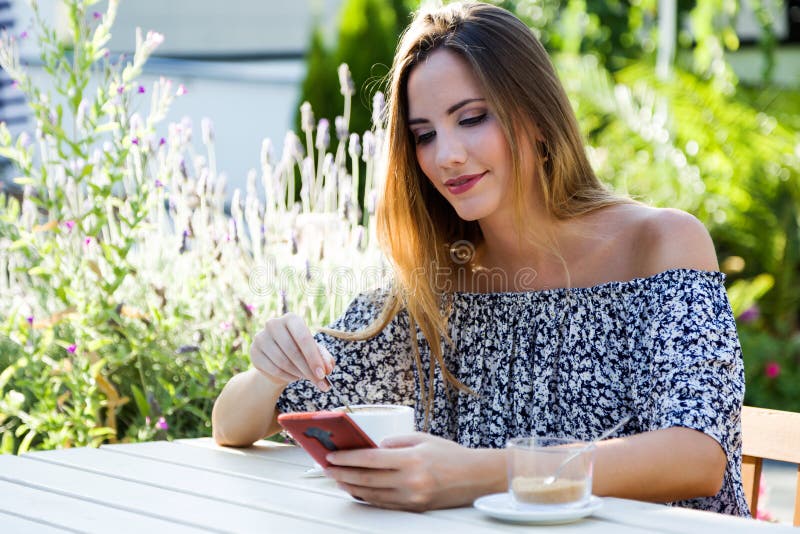 Mooie jonge vrouw die haar mobiele telefoon in de huistuin met behulp van stock foto's Mooie jonge vrouw die haar mobiele telefoon in de huistuin met behulp van stock foto's
