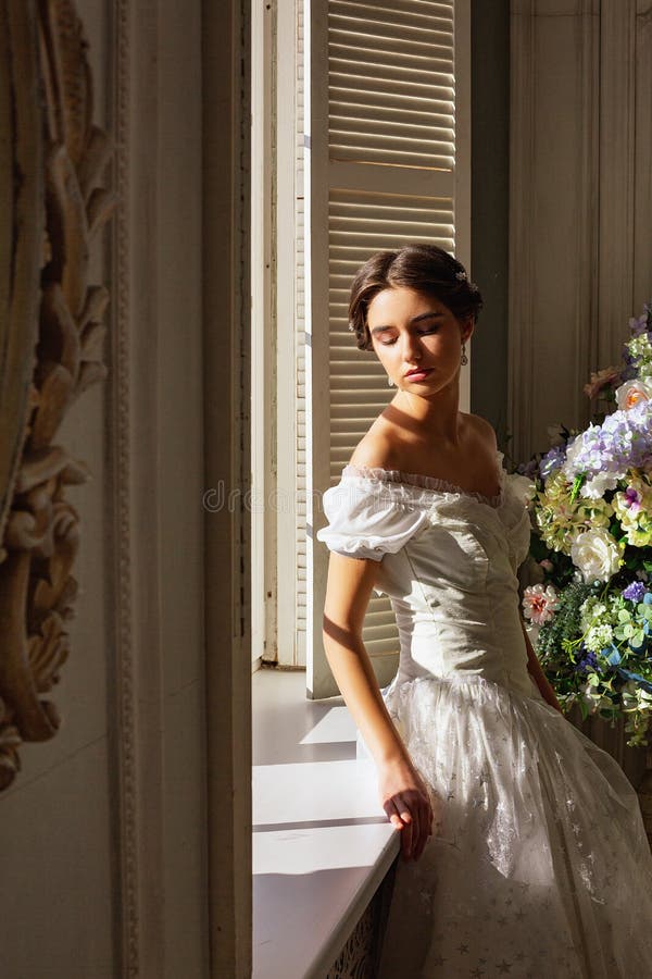 Mooie jonge vrouw die zich in witte kleding dichtbij spiegel bevinden royalty-vrije stock afbeelding Mooie jonge vrouw die zich in witte kleding dichtbij spiegel bevinden royalty-vrije stock afbeelding