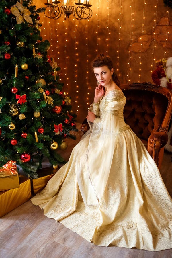 Mooie jonge vrouw in een mooie kledingszitting bij de Kerstboom met giften, Kerstmis en nieuw jaar royalty-vrije stock fotografie Mooie jonge vrouw in een mooie kledingszitting bij de Kerstboom met giften, Kerstmis en nieuw jaar royalty-vrije stock fotografie