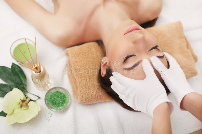 Mooie jonge vrouw gezichtsmassage krijgen die liggend op de laag stock afbeeldingen Mooie jonge vrouw gezichtsmassage krijgen die liggend op de laag stock afbeeldingen