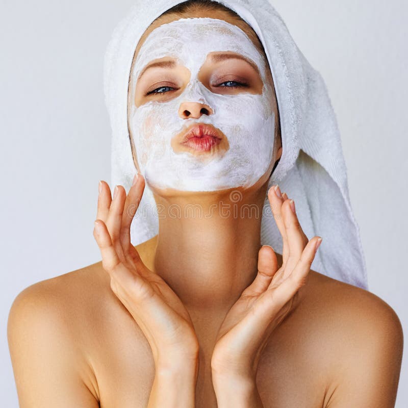 Beautiful young woman with facial mask on her face. Skin care and treatment, spa, natural beauty and cosmetology concept, over white background. Beautiful young woman with facial mask on her face. Skin care and treatment, spa, natural beauty and cosmetology concept, over white background