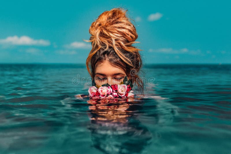 Mooie jonge vrouw zwemt in zee met een grote conceptuele mode portret