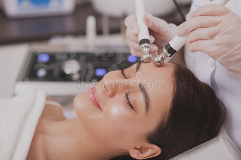 Mooie jonge vrouwen bezoekende cosmetologist bij schoonheidskliniek stock fotografie Mooie jonge vrouwen bezoekende cosmetologist bij schoonheidskliniek stock fotografie