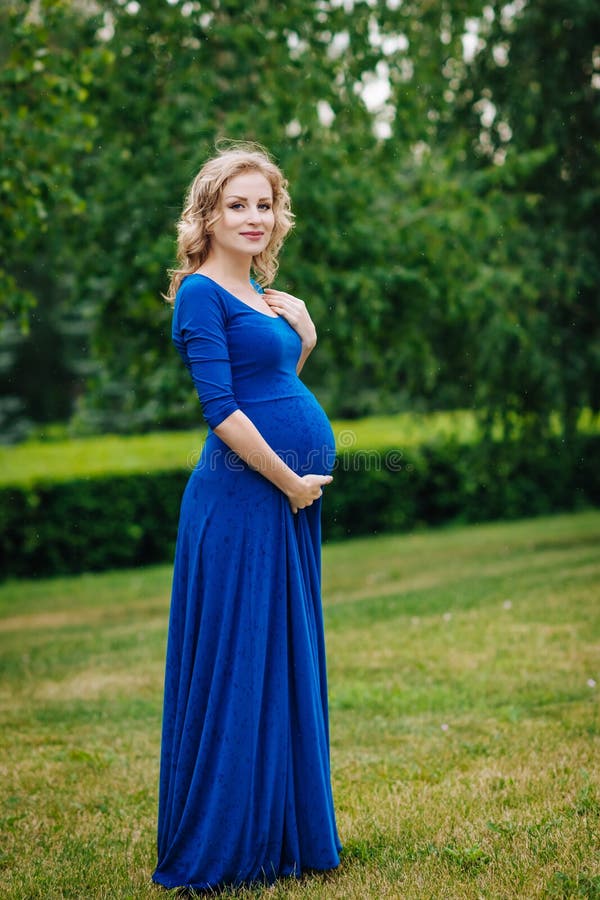 Mooie jonge zwangere vrouw in blauwe kleding met lang haar royalty-vrije stock afbeelding Mooie jonge zwangere vrouw in blauwe kleding met lang haar royalty-vrije stock afbeelding