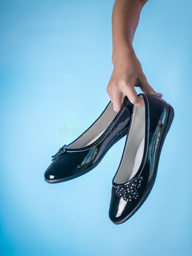Mooie leren schoenen in de hand van een kind op een blauwe achtergrond royalty-vrije stock foto Mooie leren schoenen in de hand van een kind op een blauwe achtergrond royalty-vrije stock foto