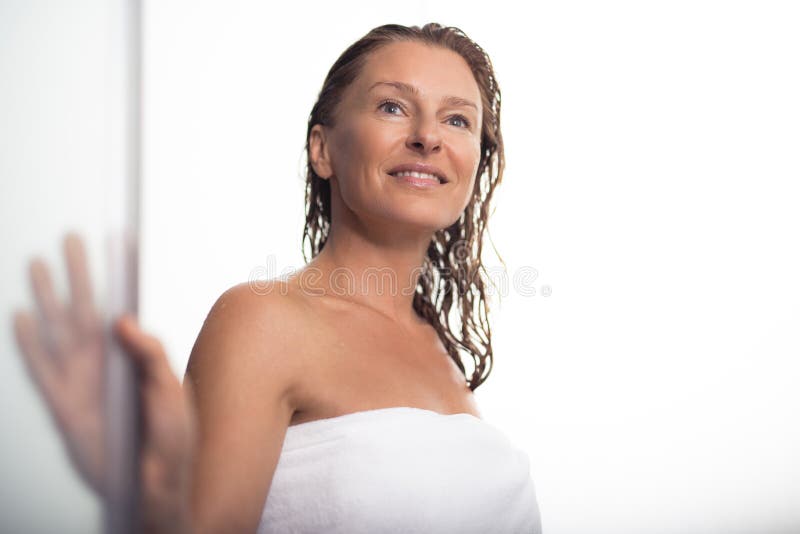 Mooie midden oude vrouw die zich na douche op witte achtergrond bevinden stock afbeeldingen Mooie midden oude vrouw die zich na douche op witte achtergrond bevinden stock afbeeldingen
