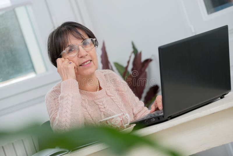 Mooie middenleeftijdsvrouw die laptop in huis met behulp van royalty-vrije stock foto's Mooie middenleeftijdsvrouw die laptop in huis met behulp van royalty-vrije stock foto's