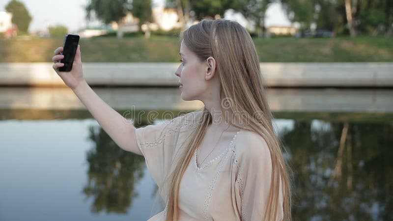 Mooie modieuze vrouw die selfie op de rivierachtergrond maken