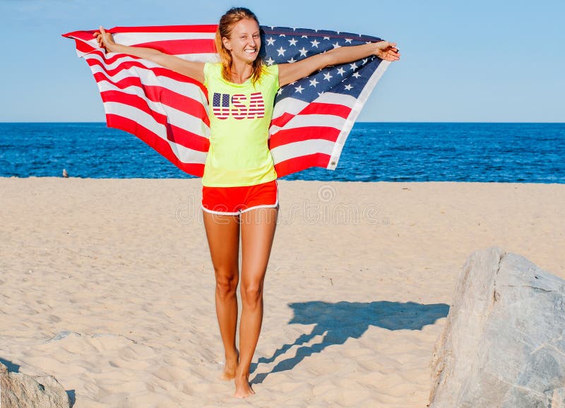 Mooie patriottische vrolijke vrouw die een Amerikaanse vlag op het strand houden royalty-vrije stock afbeelding Mooie patriottische vrolijke vrouw die een Amerikaanse vlag op het strand houden royalty-vrije stock afbeelding