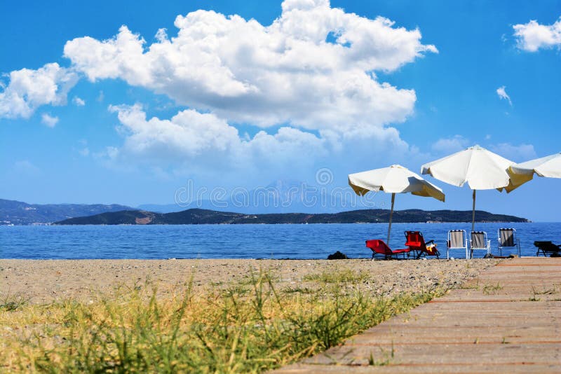 Mooie strandachtergrond met stoelen en paraplu, Griekenland Khalkidhiki stock afbeeldingen Mooie strandachtergrond met stoelen en paraplu, Griekenland Khalkidhiki stock afbeeldingen