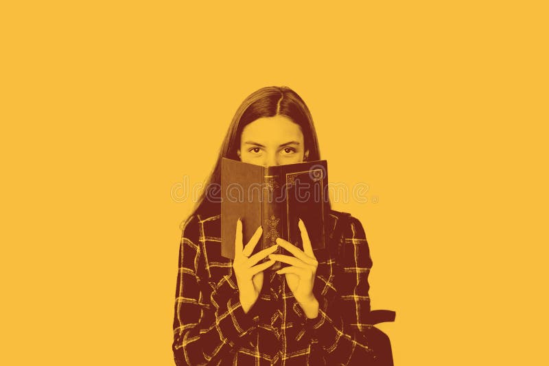 Mooie tienerstudente met boek in haar handen die gezicht met exemplaarruimte verbergen stock foto's Mooie tienerstudente met boek in haar handen die gezicht met exemplaarruimte verbergen stock foto's