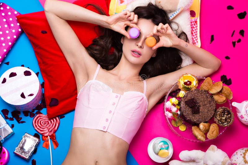 Mooie verse meisjespop die op heldere die achtergronden liggen door snoepjes, schoonheidsmiddelen en giften worden omringd De sti stock foto's Mooie verse meisjespop die op heldere die achtergronden liggen door snoepjes, schoonheidsmiddelen en giften worden omringd De sti stock foto's