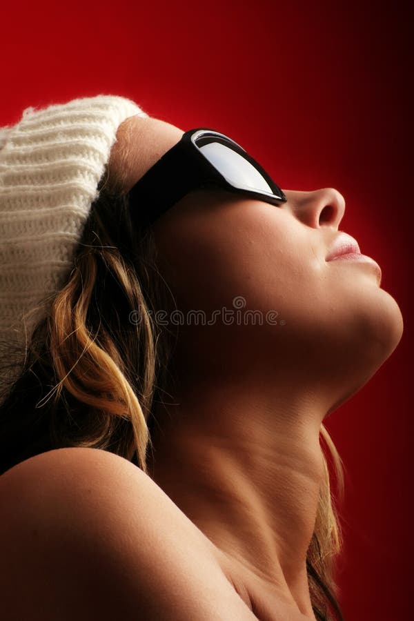 Portrait of a beautiful woman with a cap and some sunglasses against red background. Portrait of a beautiful woman with a cap and some sunglasses against red background