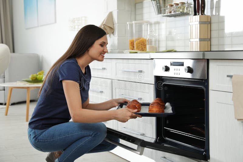 Mooie vrouw die dienblad van gebakken broodjes van oven nemen stock afbeeldingen Mooie vrouw die dienblad van gebakken broodjes van oven nemen stock afbeeldingen